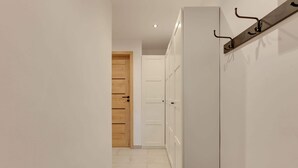 Ein Flur mit einer Holztür, einem weißen Kleiderschrank und einem Kleiderständer.