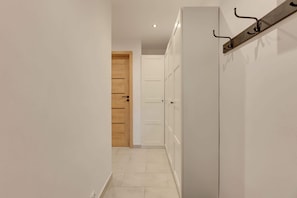 Ein Flur mit einer Holztür, einem weißen Kleiderschrank und einem Kleiderständer.