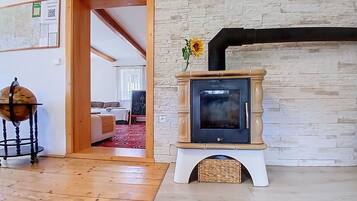 A room with a wooden floor, a stone wall, a fireplace, and a door leading to another room.