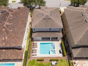 Un quartier résidentiel doté d’une piscine centrale, entourée de chaises longues et d’une petite terrasse.