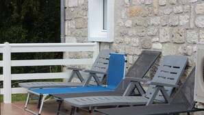 Outdoor lounge chairs with a stone wall backdrop and a white railing. - Holiday Home 'Maison Vue Sur La Tour' with Private Terrace, Wi-Fi and Air Conditioning (Montcuq-en-Quercy-Blanc)