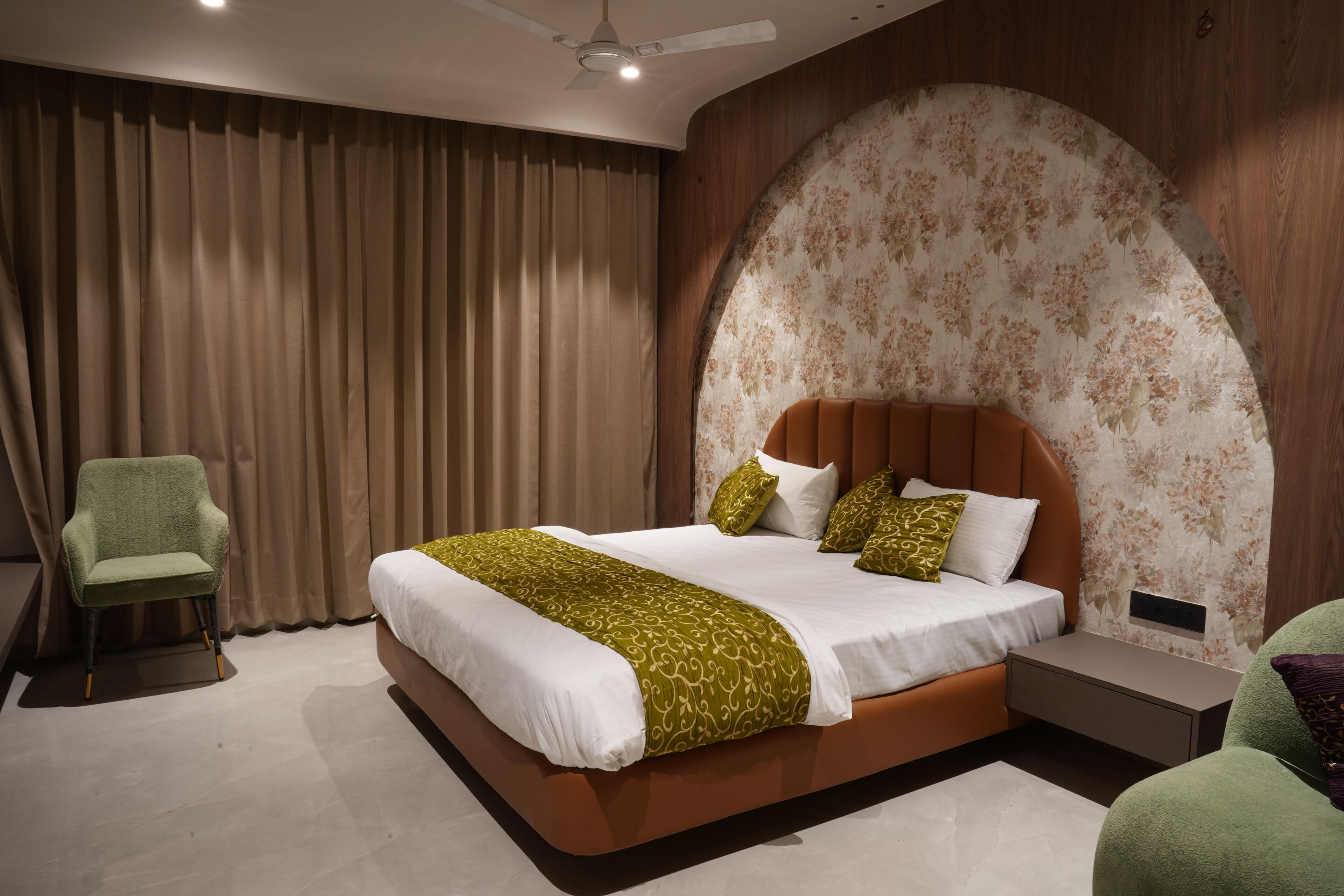 Un dormitorio moderno con una cama grande, un sillón verde y una mesita de noche.