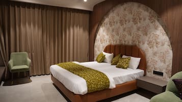 Un dormitorio moderno con una cama grande, un sillón verde y una mesita de noche.