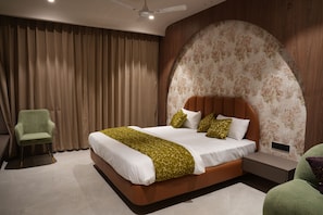 A modern bedroom with a large bed, a green armchair, and a nightstand.
