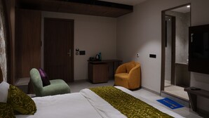Et hotelværelse med en seng, et skrivebord, en stol, et fjernsyn og et klædeskab.
