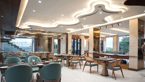 Et moderne restaurantinteriør med et centralt spiseområde, høje lofter med indbygget belysning og udsigt til det fri.