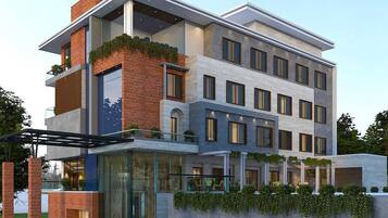 A modern multi-story hotel with a glass facade, outdoor seating area, and a mix of brick and concrete exterior.
