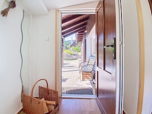 A wooden door leading to an outdoor area with a bench and a wicker basket.