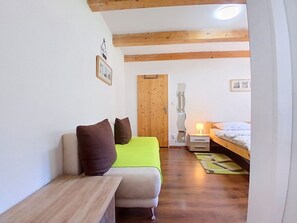 A narrow hallway with a wooden bench, a bed with a green bedspread, and a wooden door. - Cosy apartment in villa for 4 people with WIFI, TV and patio (Vrchlabí)