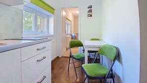 En smal gang med et hvidt skab, et vindue og en dør til et andet rum.