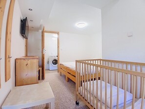 A room with a crib, a washing machine, and a small table.