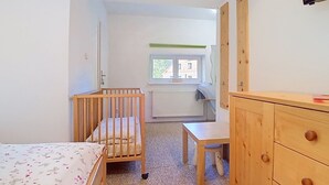 Et værelse med en rejse- eller puslebæs, et skrivebord og et klædeskab.