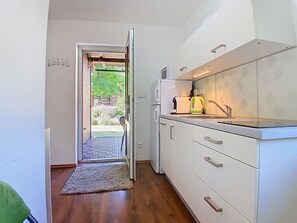 A narrow kitchen with white cabinets, a built-in oven, and a sink.