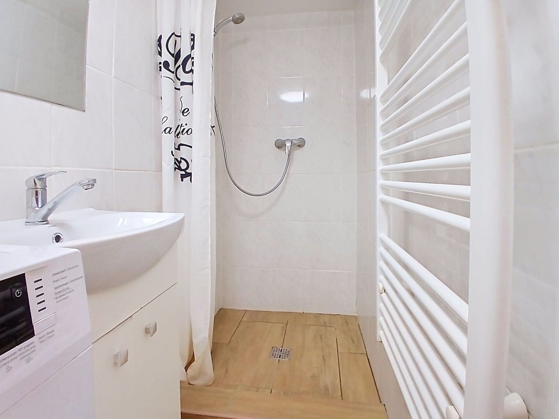A bathroom with a white sink, a shower with a glass door, and a white towel rack.
