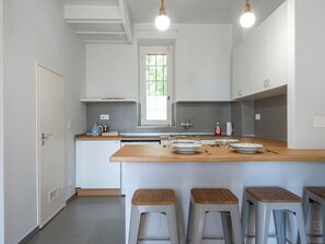 Uma cozinha moderna com uma ilha central, banquetas e uma janela.