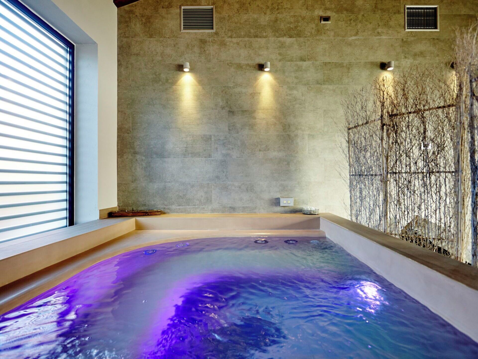 A spa area with a hot tub, stone walls, and recessed lighting.