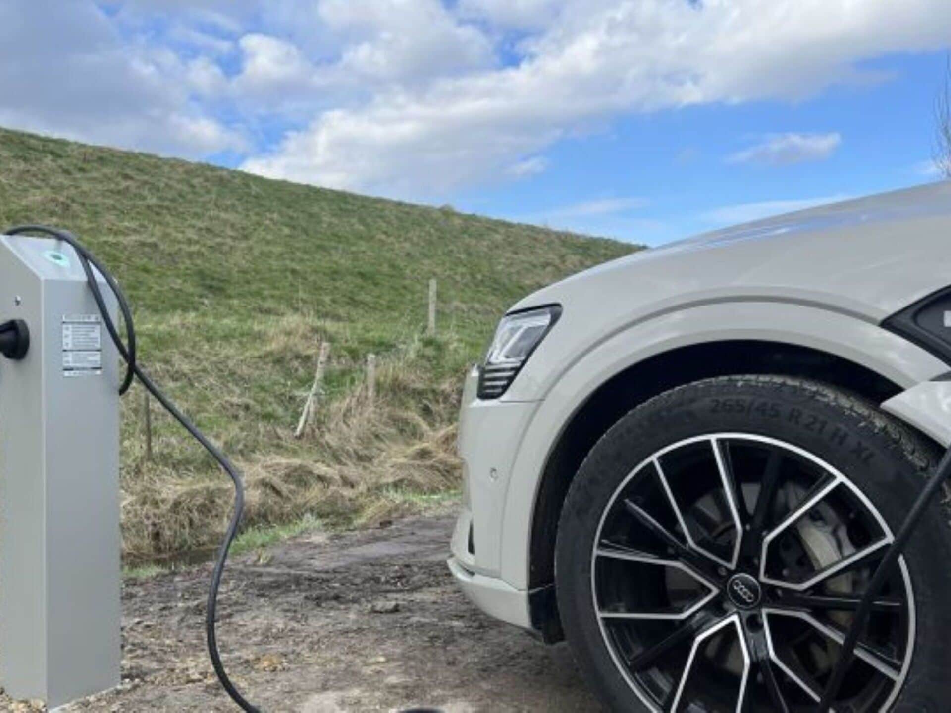 A vehicle parked near an electric charging station in a rural setting.