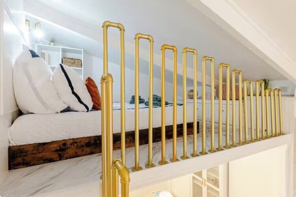 Eine Treppe mit weißer Geländer und ein Bett mit weißer Bettwäsche und Kissen.