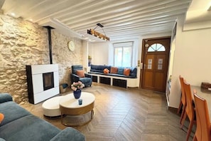 Una sala de estar con una pared de piedra, una chimenea, un sofá azul y una mesa de centro redonda.