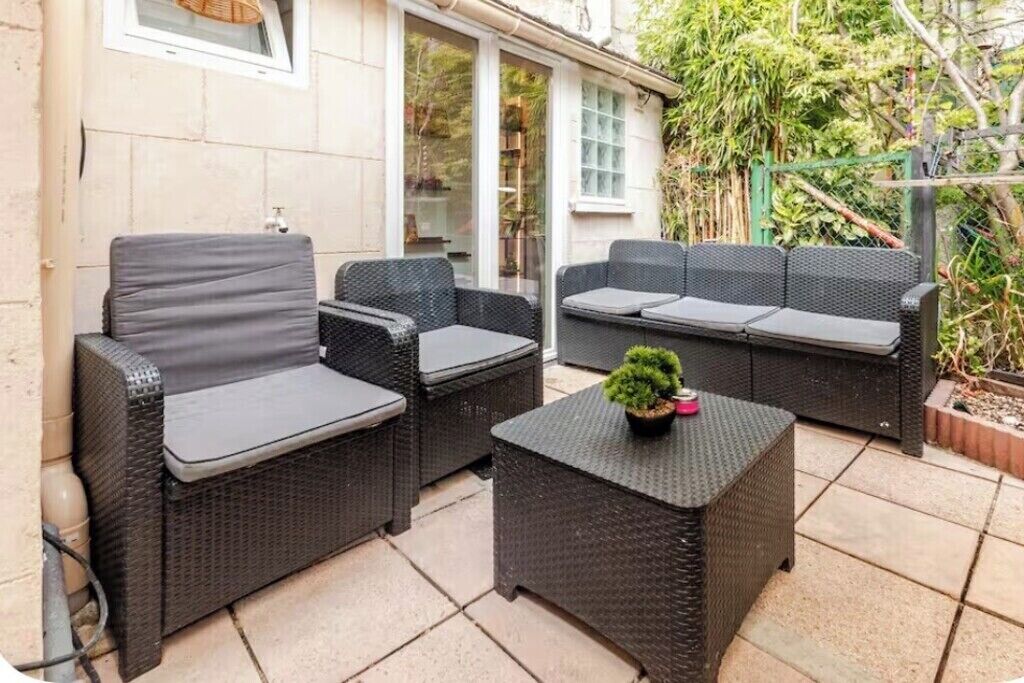 Eine Terrasse im Freien mit Korbmöbeln, darunter zwei Sofas und ein kleiner Tisch.