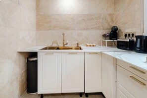 Cocina compacta con pileta, alacenas y cafetera.