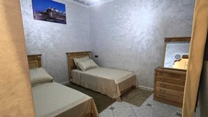 A bedroom with two beds, a wooden dresser, and a framed picture on the wall. - Wonderful 2-bedroom condo in Essaouira perfect for relaxing stays (Essaouira)