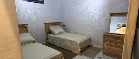 A bedroom with two beds, a wooden dresser, and a framed picture on the wall.