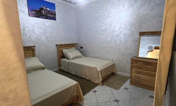 A bedroom with two beds, a wooden dresser, and a framed picture on the wall.