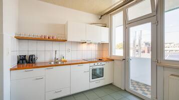 A kitchen with white cabinets, a wooden countertop, a sink, a coffee maker, and an oven.