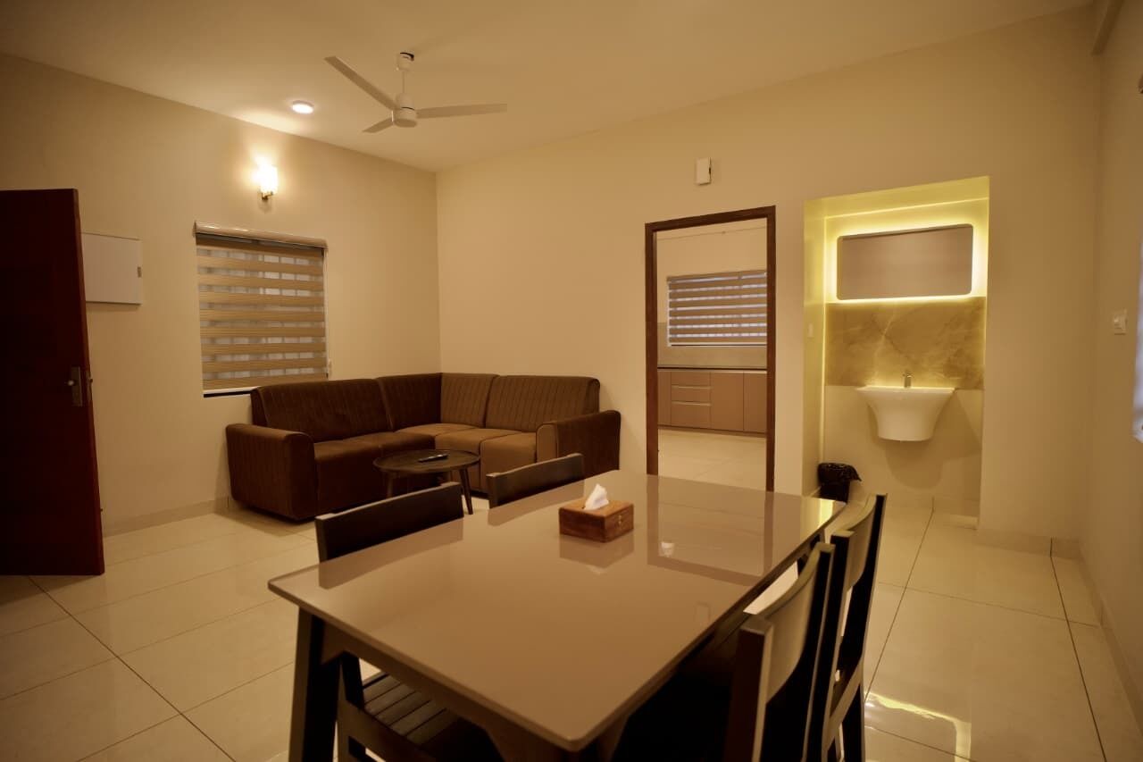 A modern living room with a sofa, a dining table, and a built-in sink.