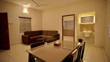 A modern living room with a sofa, a dining table, and a built-in sink.