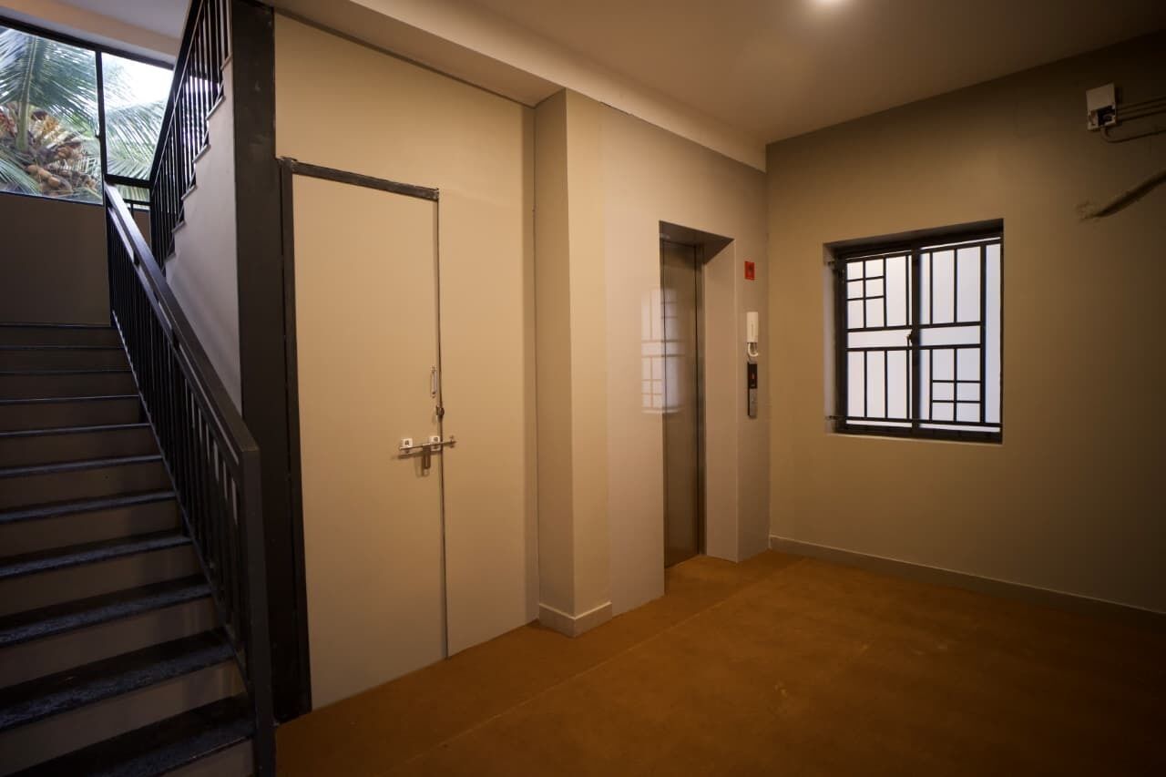 A hallway with a staircase, doors, and a window.