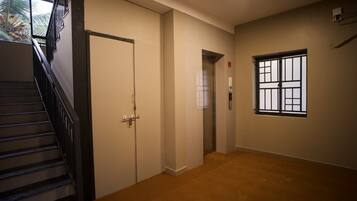 A hallway with a staircase, doors, and a window.