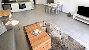 En moderne opholdsstue med et køkken, spiseplads og en siddeplads med sofalounge og sofabord.
