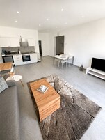 Un espacio habitable moderno con cocina, comedor y zona de estar con mesa de centro y sofá.