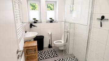 Een moderne badkamer met douche, toilet en wastafel.