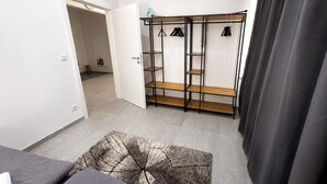 A room with a wardrobe, a door leading to another room, and a patterned rug. - Apartment mit Terrasse (Bielefeld)