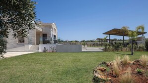 Uma casa moderna com fachada de pedra, um pátio com mobiliário de exterior e um gramado bem cuidado.