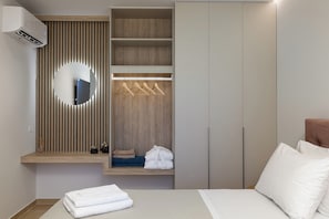 A bedroom with a bed, a wardrobe, a mirror, and a hanging robe rack. - Twin Revi Villas | Private Retreat in Stavros (Stavros)