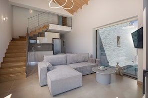 Una sala de estar moderna con un sofá, una mesa de centro y una escalera que lleva a una cocina.