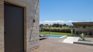 Uma área externa moderna com piscina, churrasqueira e um muro de pedra.