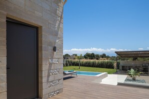 Ein moderner Außenbereich mit Pool, Grillplatz und einer Steinmauer.