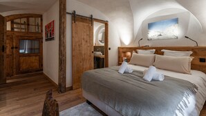 A bedroom with a large bed, wooden walls, a wooden door, and a painting on the wall.