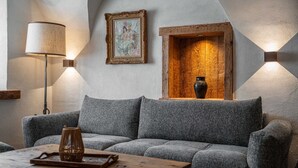 A cozy living room with a grey sofa, a wooden coffee table, a lamp, and a framed artwork above a wooden cabinet.