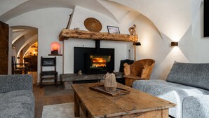 A cozy living room with a fireplace, wooden furniture, and a stone fireplace surround.