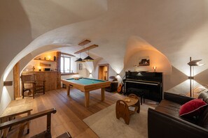Un accogliente loft con tavolo da biliardo, pianoforte e divano.
