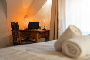 Ein Schlafzimmer mit Schreibtisch aus Holz, einem Laptop, einer Kerze und zusammenge rollten Handtüchern.
