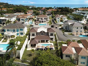 Un barrio residencial con varias casas, una piscina central y vista al océano.