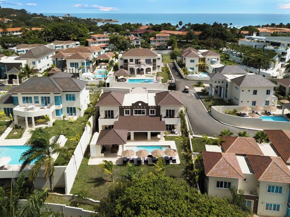Un quartiere residenziale con diverse case, una piscina centrale e vista sull'oceano.