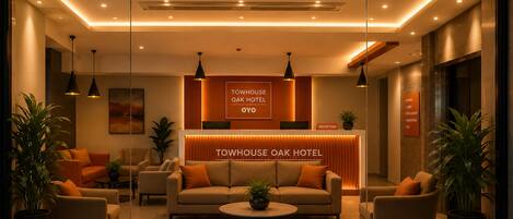 A hotel reception area with a reception desk, sofas, and potted plants.